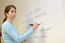 Woman using white static-cling whiteboard film applied to painted drywall with dry erase markers